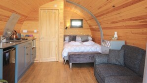 A cozy, wooden interior with a bed, bench, and kitchenette. - Paradise (Market Drayton)
