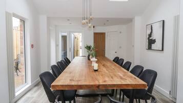 Un comedor amplio con una larga mesa de madera, sillas negras y un florero central con flores.