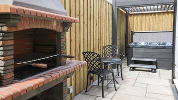 Un patio al aire libre con una parrilla de ladrillo, dos sillas de metal y una estufa a gas.