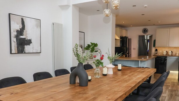 A modern dining area with a wooden table, black chairs, and decorative vases. - Seascape Villa (Filey)