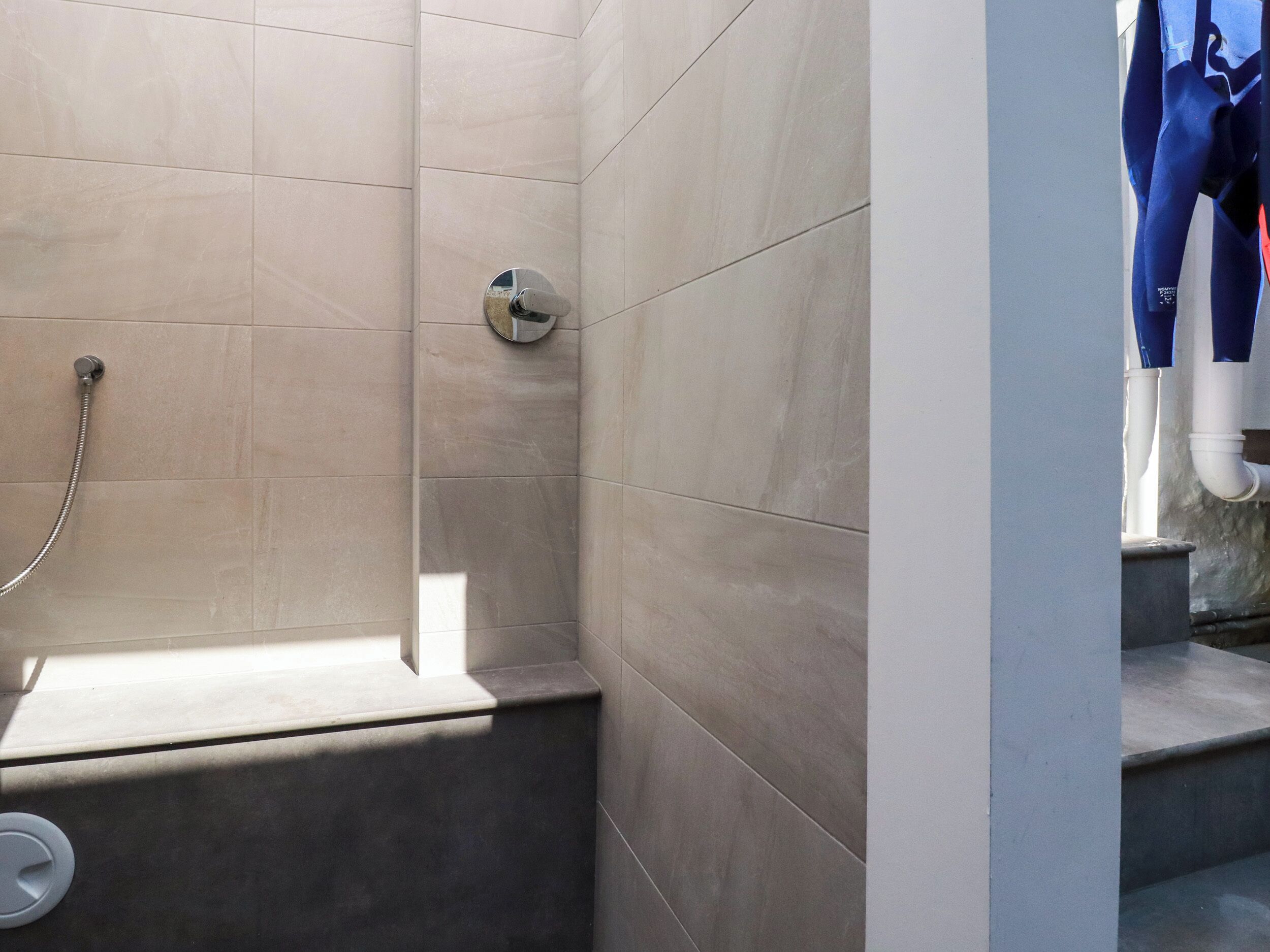 Une salle de bain moderne avec un espace douche, des murs carrelés et des toilettes apparentes.
