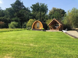 Une cabane en bois avec un toit incurvé, un petit porche et une statue de cygne dans la cour.