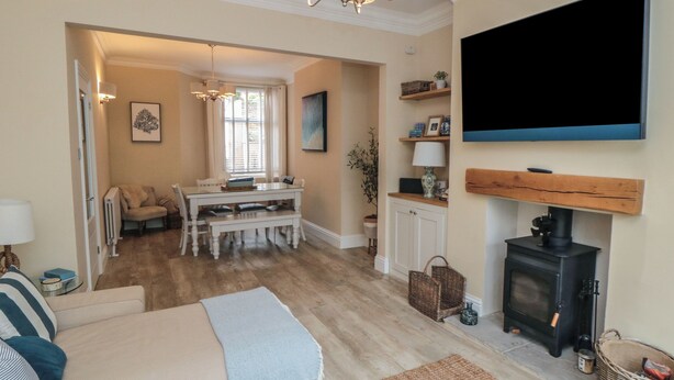 A cozy living room with a fireplace, a dining area, and a TV mounted on the wall. - Thirty Four By the Sea (Scarborough)