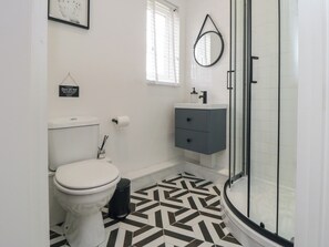 A bathroom with a toilet, a sink, a mirror, and a shower. - Thirty Four By the Sea (Scarborough)