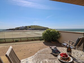 A terrace with a view of the beach, a bottle of wine, and a plate of strawberries. - 6 Burgh Island (Kingsbridge)