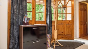 A wooden-framed room with a black cabinet, a stand with books, and a door with a wooden panel. - Mill Cottage (Exeter)