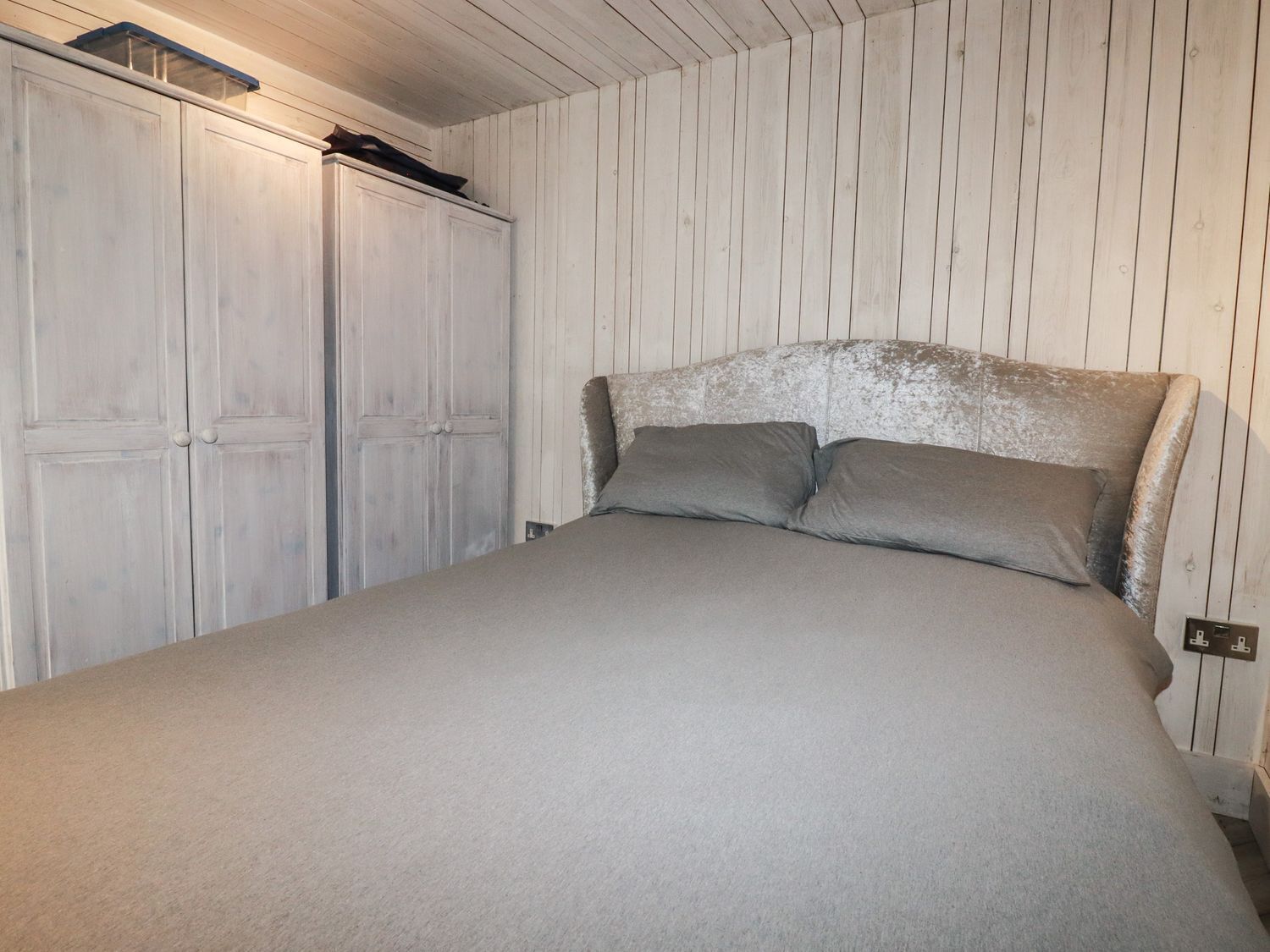 A bedroom with a bed, two wardrobes, and a wooden ceiling.