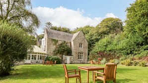 Un edificio de piedra con un amplio jardín y zona de estar al aire libre.