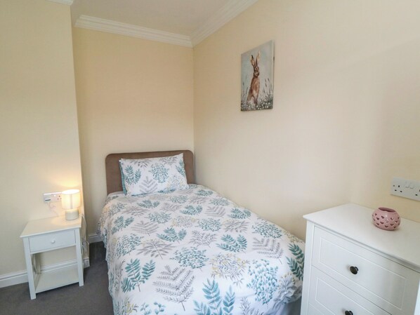 Una camera da letto con un letto, un comodino, una cassettiera e un quadro appeso al muro.