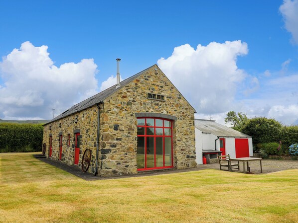 A stone building with red doors and windows, a chimney, and a small adjacent white building with a red door. - West Dairy (Newport)