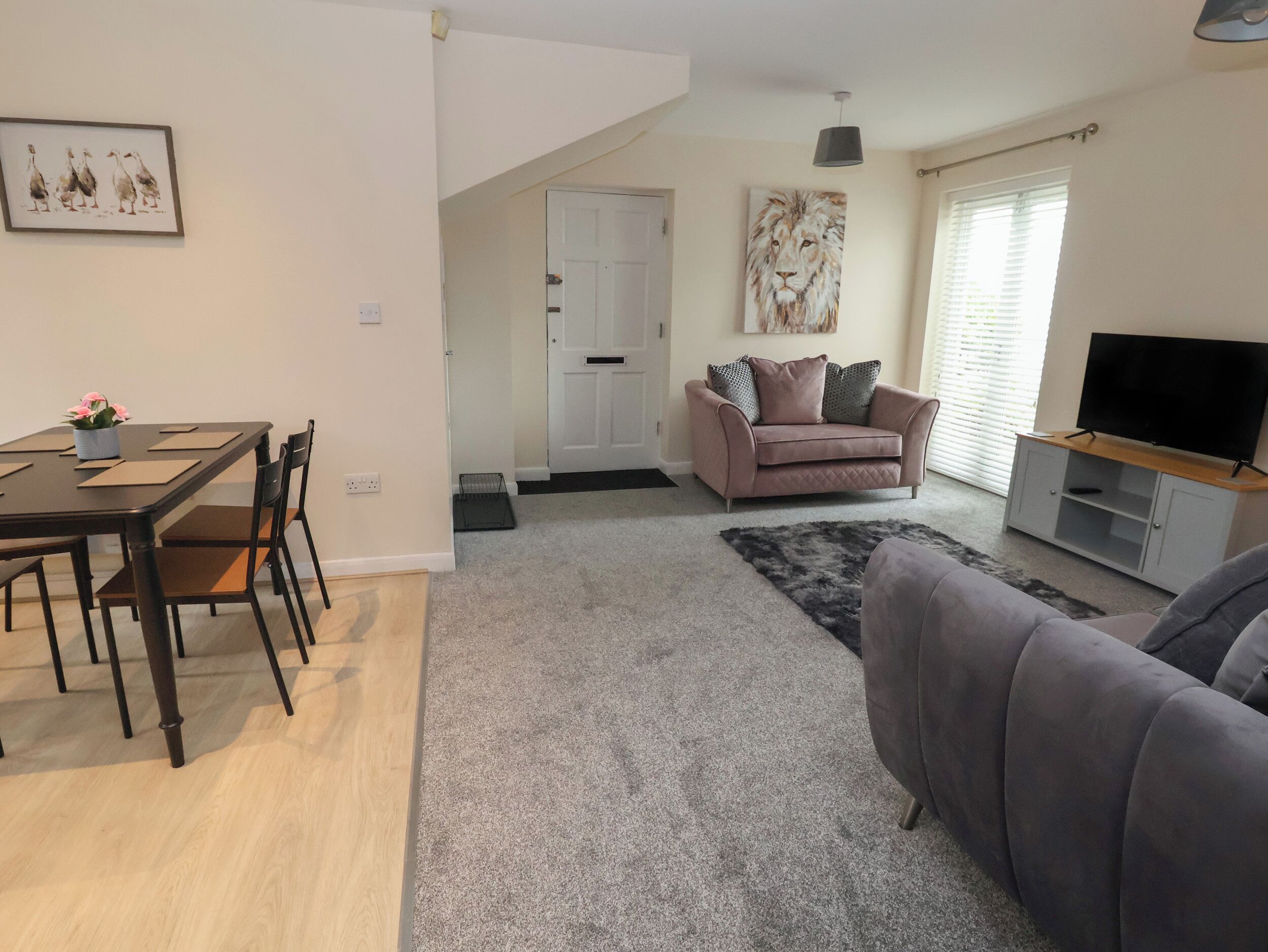 Una sala de estar con sofá, mesa de centro, mueble para la televisión y comedor con mesa y sillas.