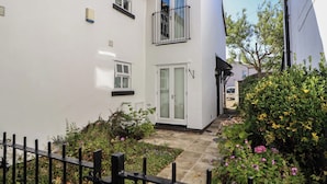 A two-story house with a white exterior, a small front garden, and a black metal fence.
