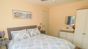A bedroom with a bed, nightstands, a dresser, a mirror, and a door. - 6 Fairfax Close (York)