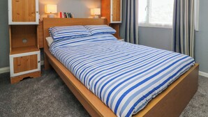 A single bed with a wooden headboard, striped bedding, and built-in wooden cabinets above. - 4 The Park (Bude)