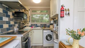 A compact kitchen with a washing machine, a stove, and a sink. - 4 The Park (Bude)
