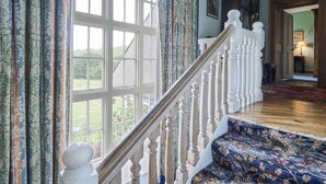 A staircase with white balusters leading to a landing with a patterned carpet. - Plas Pontfaen (Fishguard)