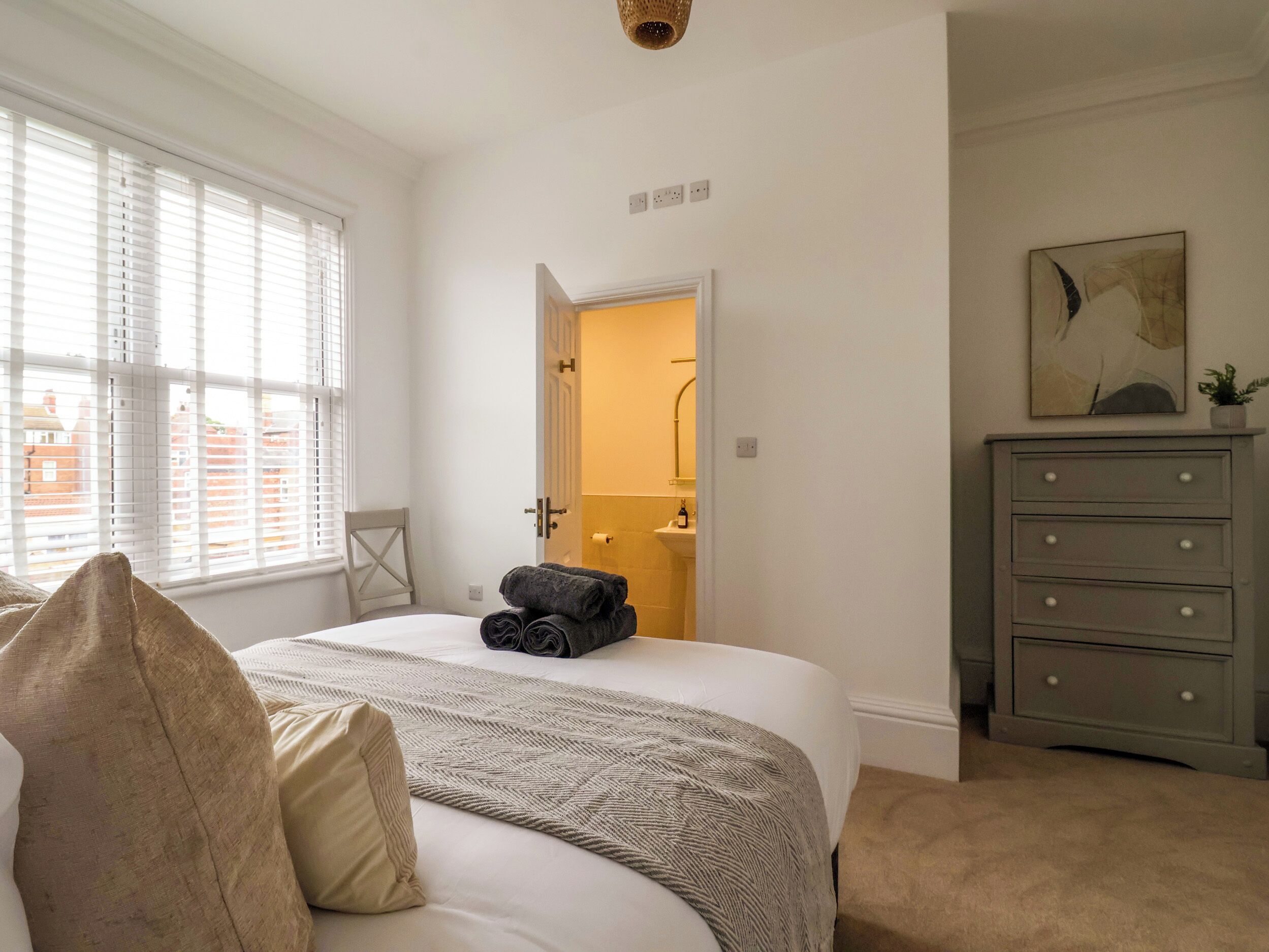 Un dormitorio con cama, cómoda y ventana con persianas.