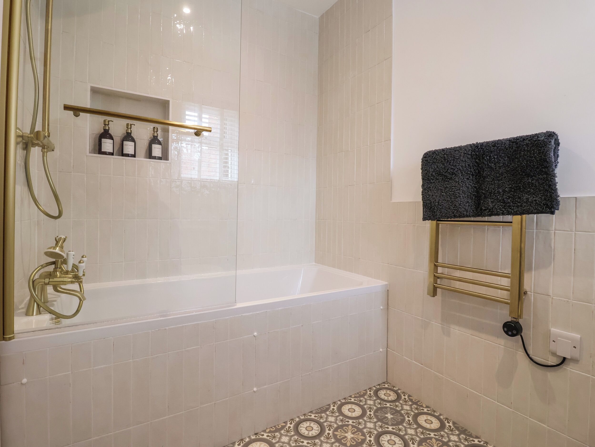A bathroom with a bathtub, a shower, and a towel rack.