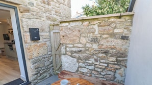 Un mur de pierres avec un banc en bois et une table sur laquelle se trouvent deux tasses et une théière.
