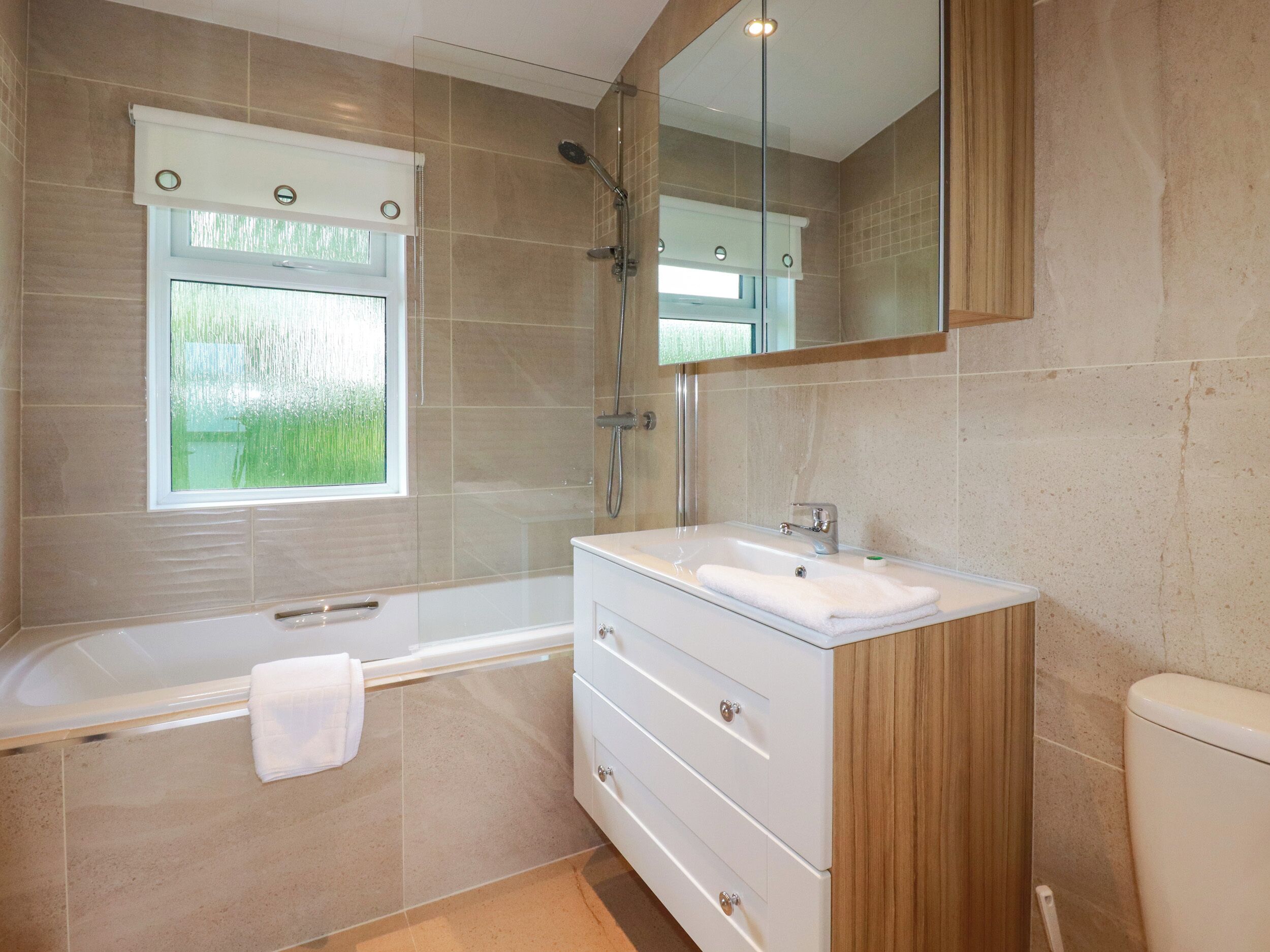 A modern bathroom with a bathtub, a sink, and a mirror.