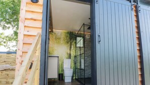Une salle de bain moderne et compacte, dotée d’une douche à parois de verre et de toilettes blanches.