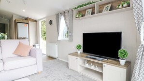 Ein modernes Wohnzimmer mit einem weißen Sofa, einem Flachbildfernseher auf einem Holz-TV-Möbel und Zimmerpflanzen.