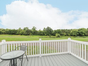 A deck with a white railing, a table, and a chair. - Stork Lodge (Coalville)