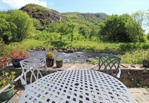 Una mesa y sillas en un jardín con vistas a un río y colinas.