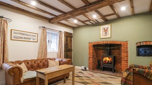 A cozy living room with a leather sofa, a wooden coffee table, a fireplace, and a patterned rug. - 2 Loxter Villas (Ledbury)