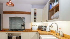A modern kitchen with white cabinetry, a wooden countertop, a built-in oven, a microwave, a toaster, and a sink. - 2 Loxter Villas (Ledbury)