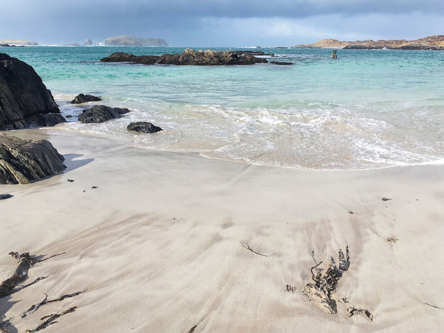 Una platja amb aigua turquesa cristal·lina, roques i una riba sorrenca.