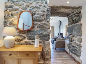 Una habitación con paredes de piedra, un tocador de madera, un espejo y una lámpara.