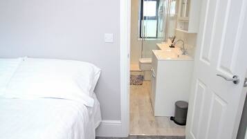 Un dormitorio con cama, un baño con ducha y un inodoro.