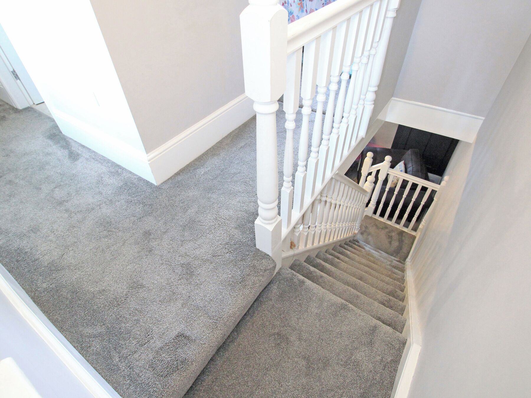 A staircase with a grey carpet leading to a lower level.