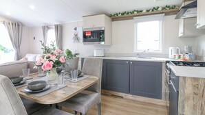 A modern kitchen with grey cabinets, a wooden dining table, and a built-in stove.