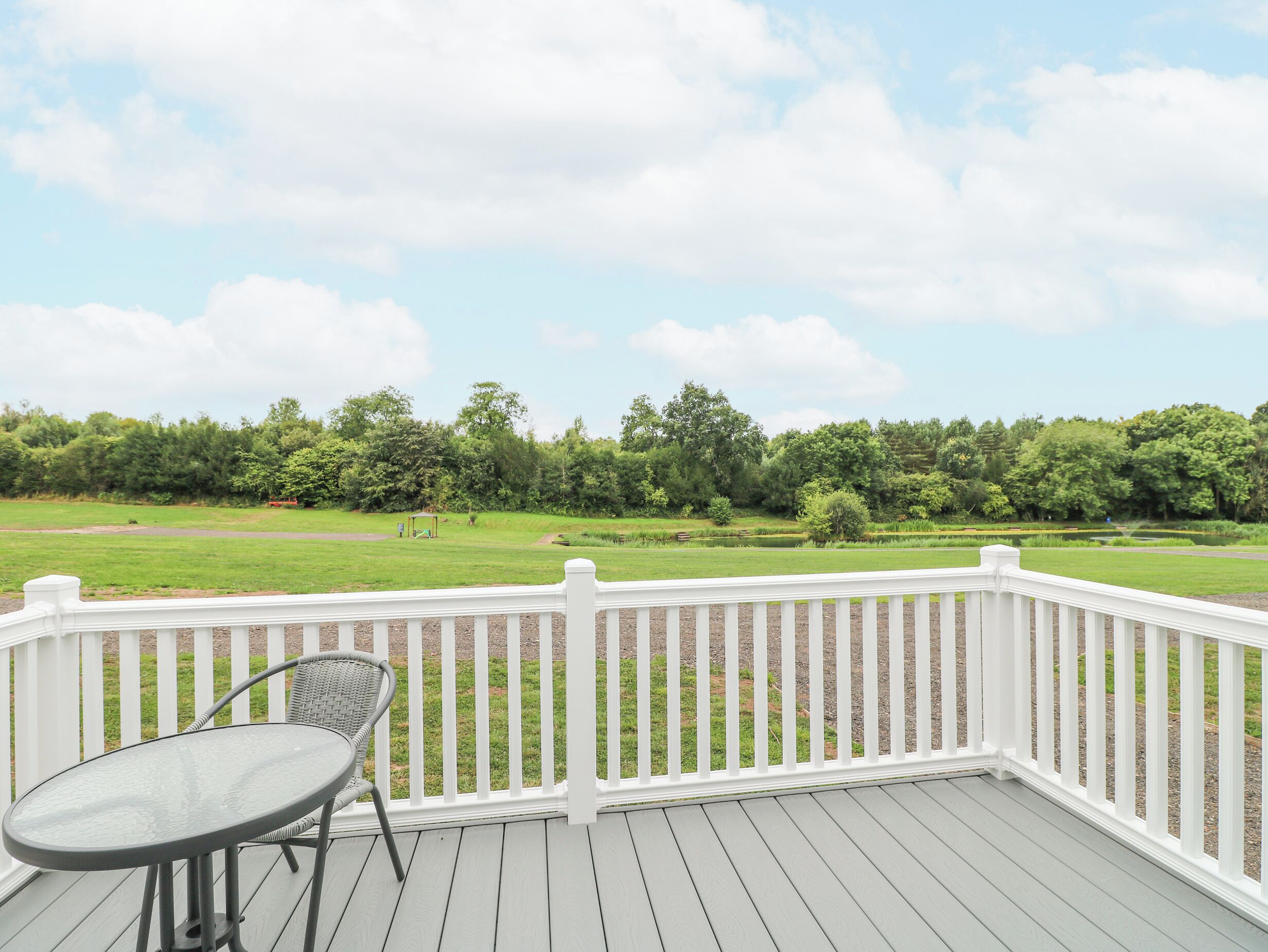 A deck with a white railing, a round table, and a chair.