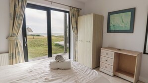 Une chambre à coucher avec un lit, une armoire en bois, un bureau et une vue sur la mer.