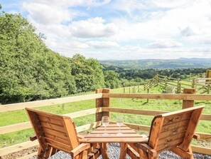 A wooden deck with a table and chairs overlooking a scenic landscape. - Shepherd's Cwtch (Llandovery)