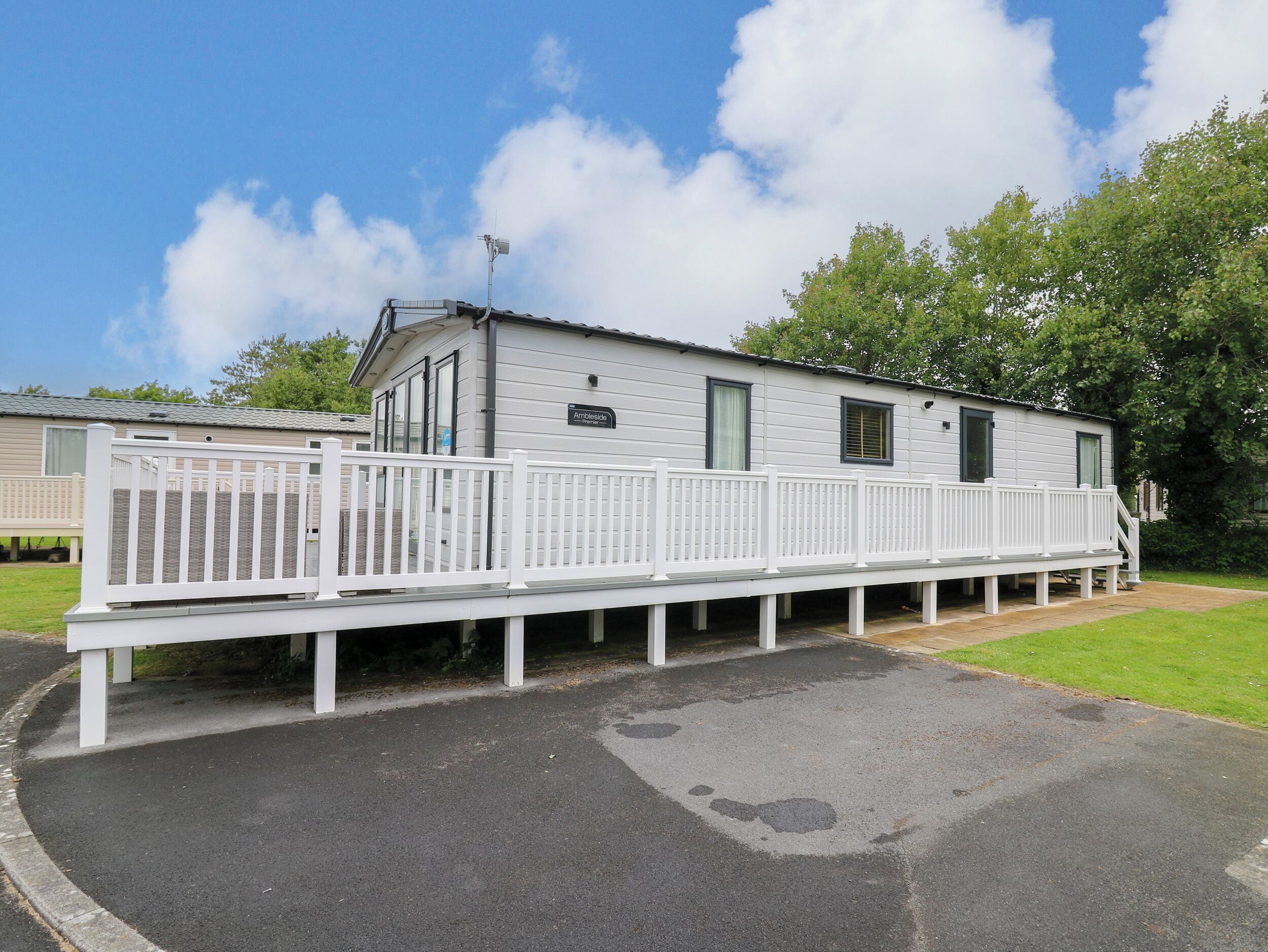 A mobile home with a white deck and a small porch.