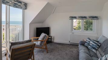 A modern living room with a large window, a TV, a sofa, and a chair.