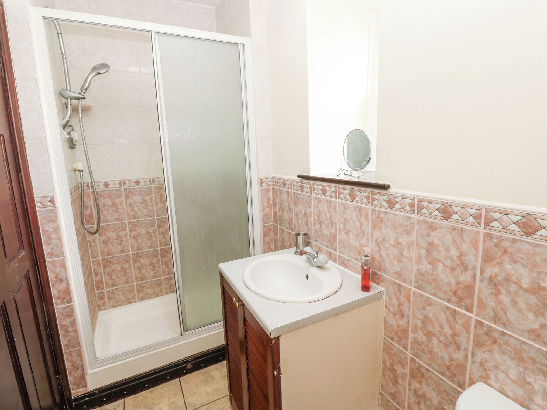 A bathroom with a shower, sink, and mirror.