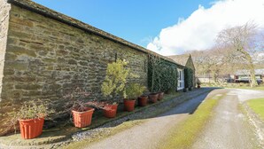 A stone building with a gravel driveway and potted plants along the side. - Pencroft Cottage (Leyburn)