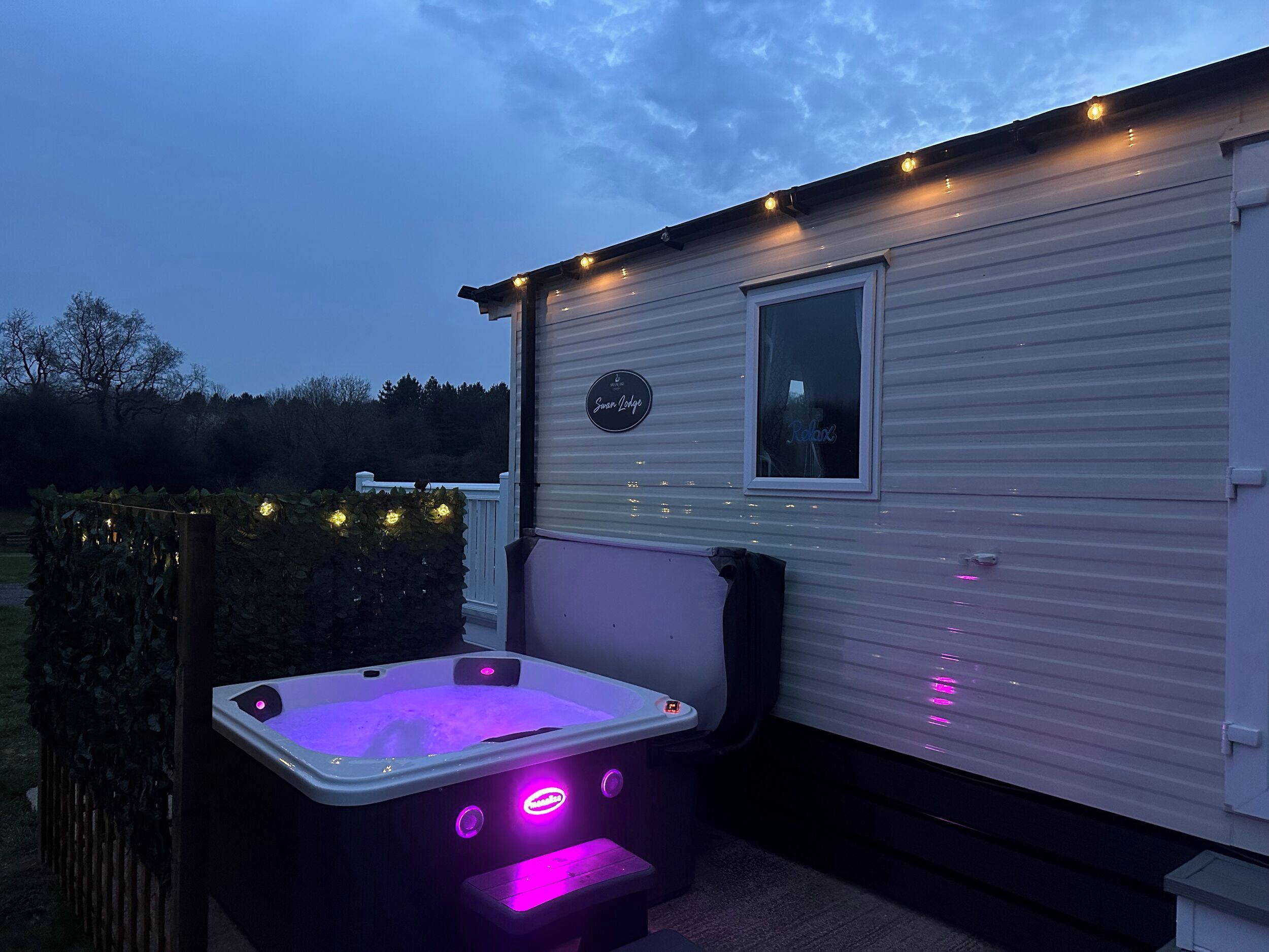 Une caravane équipée d’un jacuzzi et illuminée de guirlandes lumineuses.