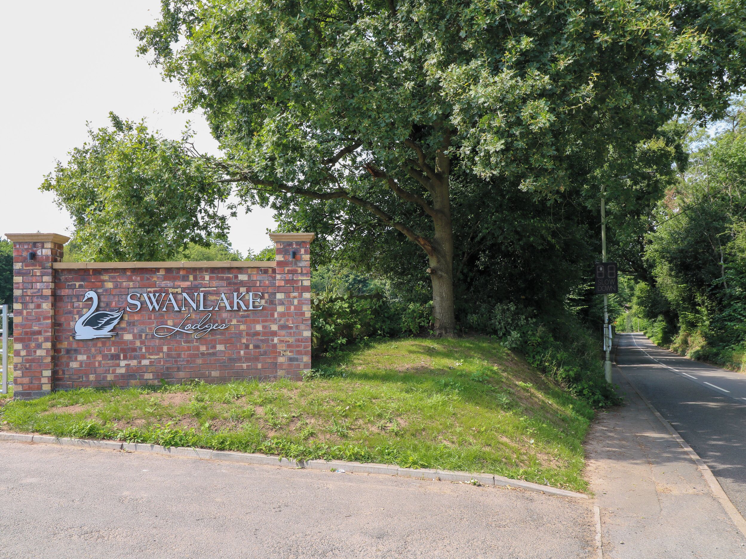 A brick wall with the sign "SWANLAKE Lodges" and a swan logo.