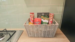 Egy fonott kosár a konyhapulton, benne különféle kávé- és teafajták.