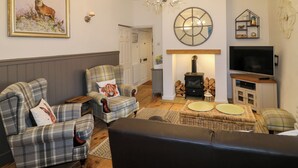 A cozy living room with plaid furniture, a fireplace, a television, and a chandelier. - The Hideout (Oakham)