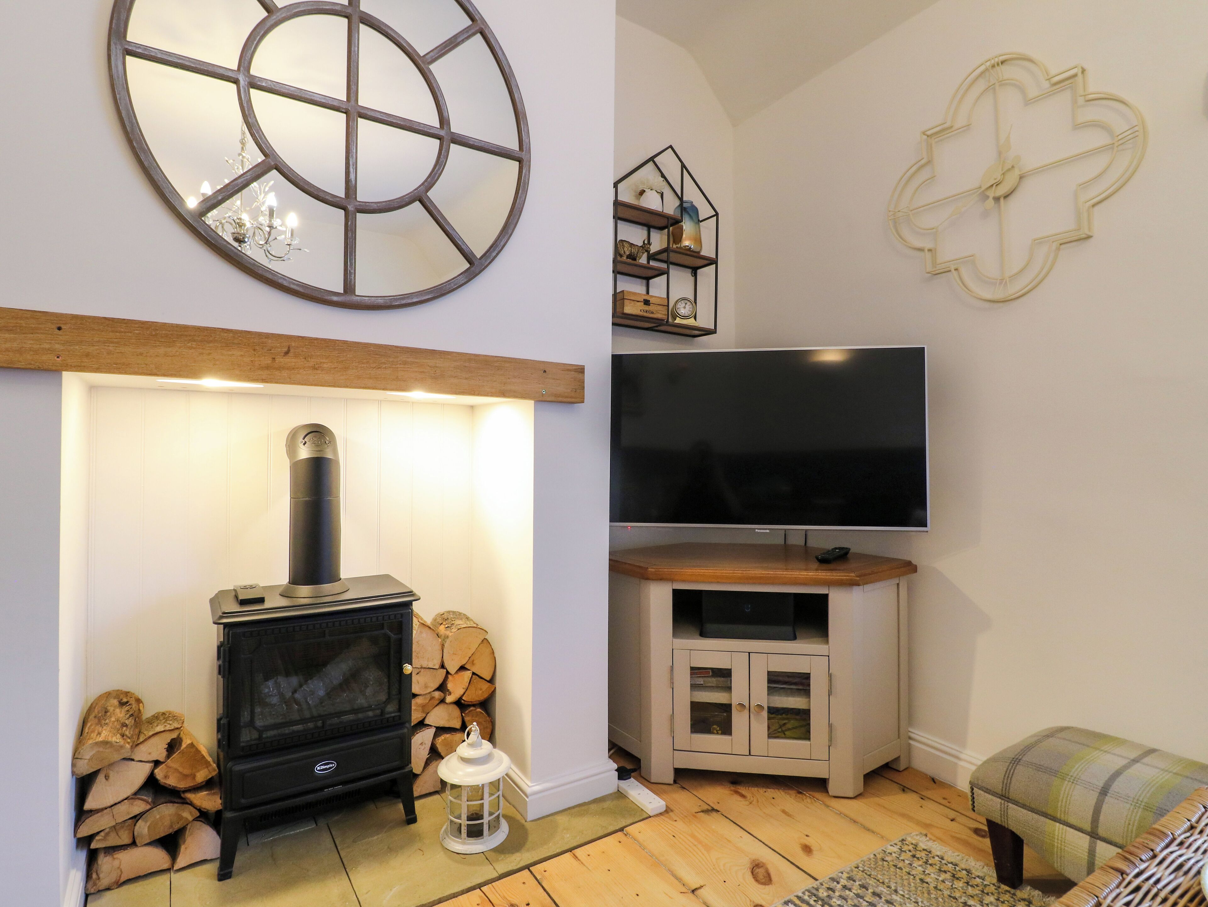 Una sala de estar acogedora con una chimenea de leña, un televisor de pantalla plana y decoración mural.