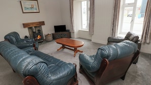 Una sala de estar con chimenea, sofás de cuero, una mesa de centro de madera y un televisor.