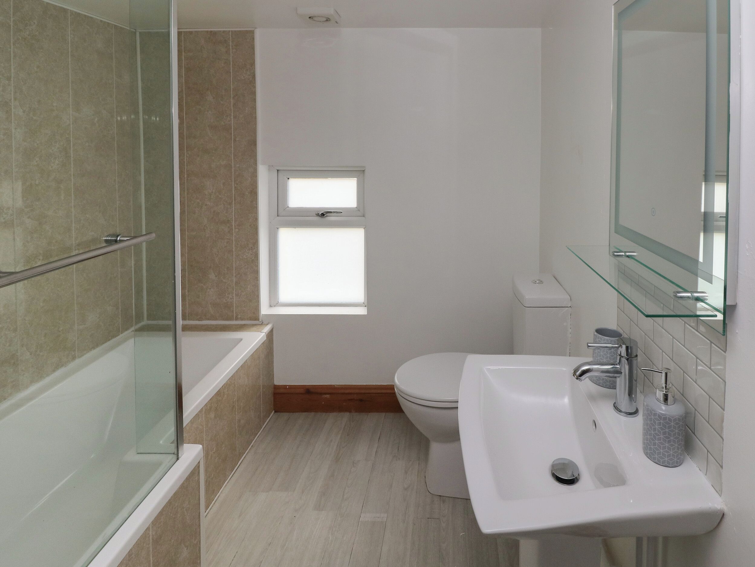 Un baño moderno con cabina de ducha de vidrio, inodoro y lavamanos con repisa de cristal.