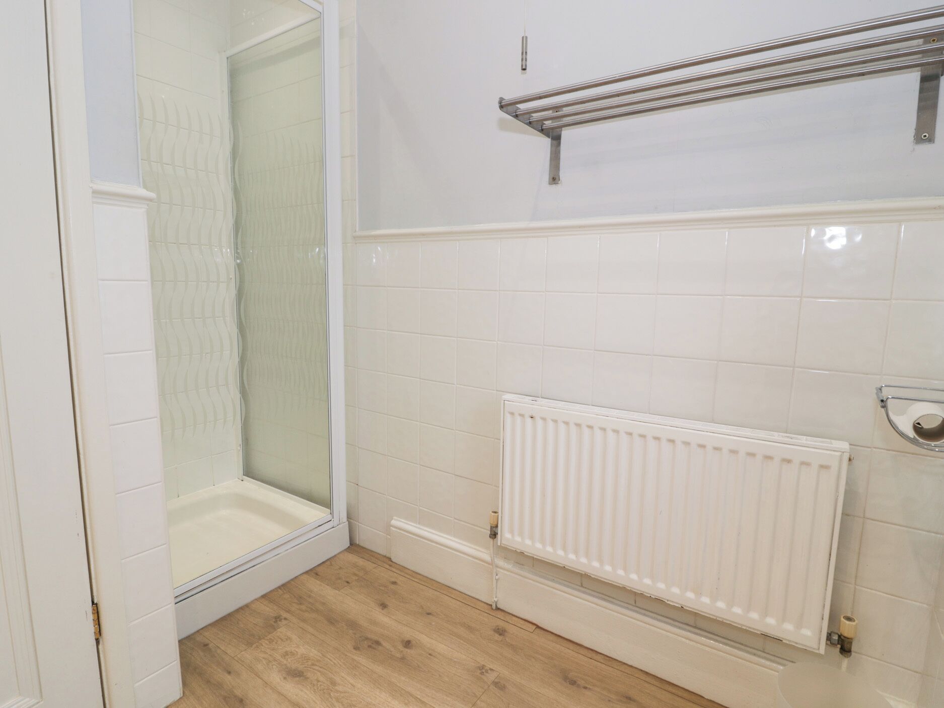 A bathroom with a shower, a toilet, and a radiator.